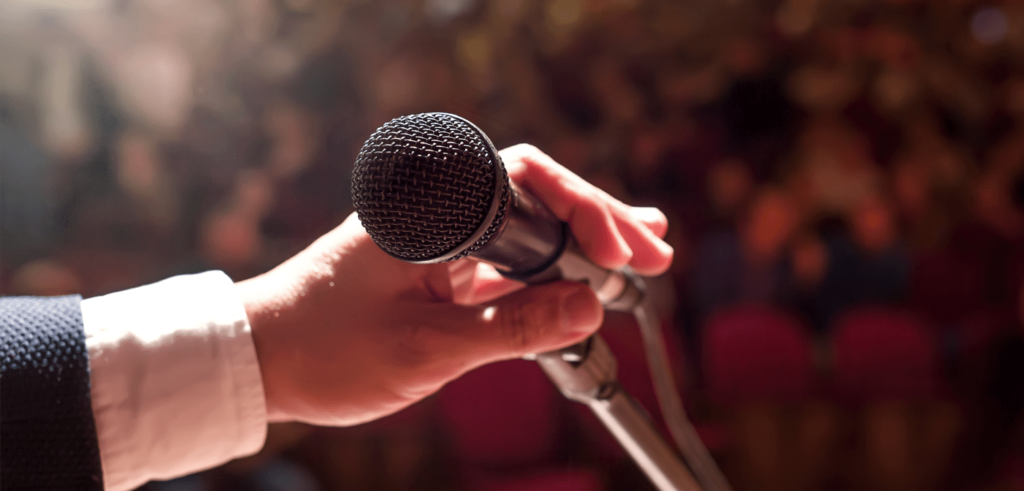 a businessman holding a mic as he is about to address an audience with a speech